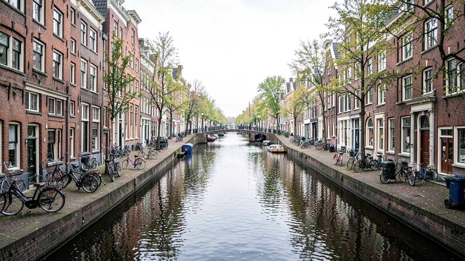 Visitors walking along an Amsterdam canal lined with bicycles and narrow houses